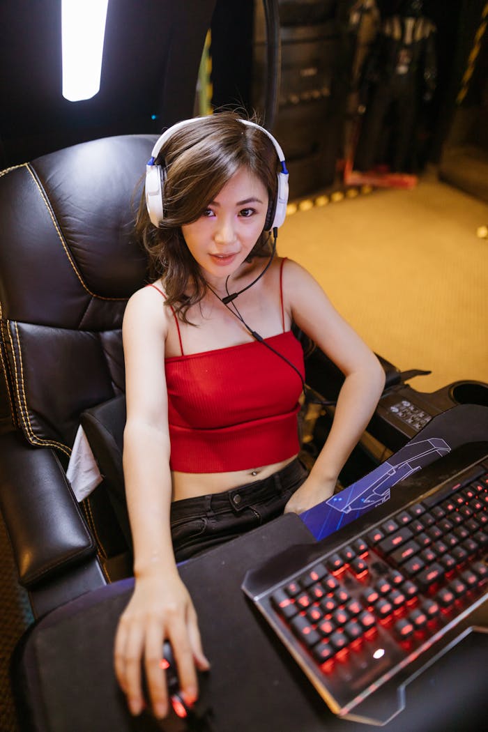 A woman with headphones enjoying a gaming session with high-end equipment indoors.